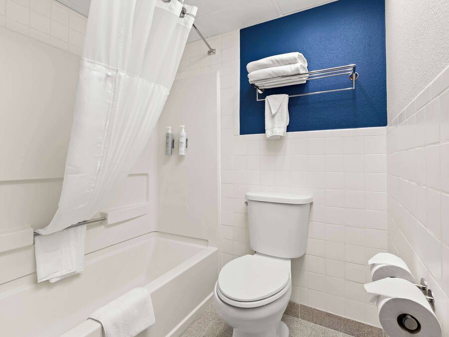 A bathroom with a bathtub, toilet, and a towel rack with towels.