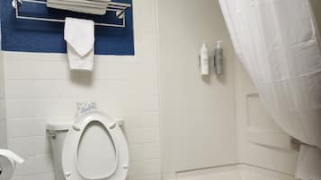 Un baño con inodoro, bañera, cortina de ducha y toallero.