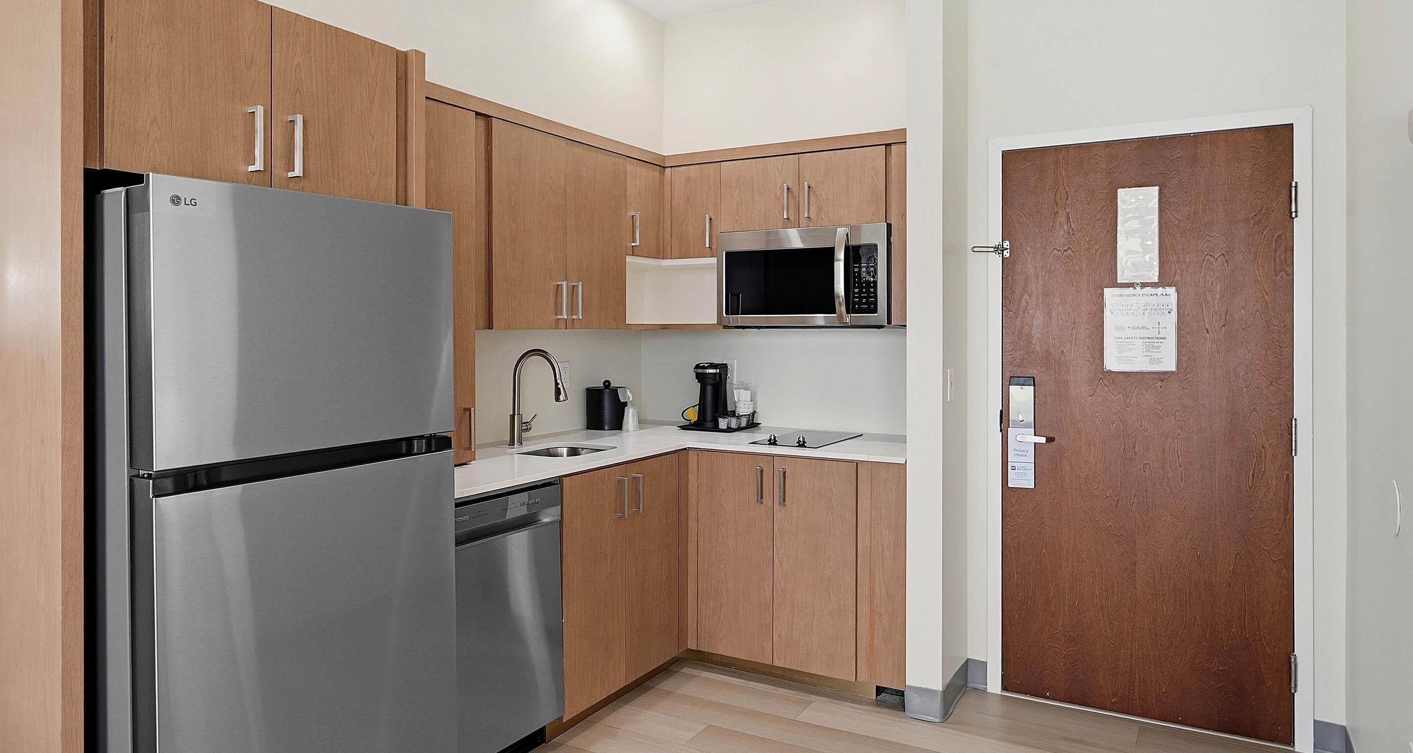 A modern kitchen with wooden cabinets, stainless steel appliances, and a white countertop.