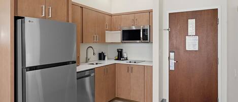 Una cocina moderna con armarios de madera, electrodomésticos de acero inoxidable y encimera blanca.