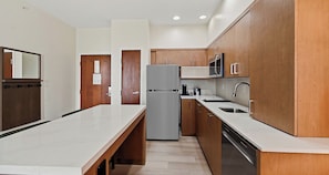 A modern kitchen with wooden cabinets, a stainless steel refrigerator, and a built-in oven. - Best Western Plus Hannaford Inn & Suites (Cincinnati)