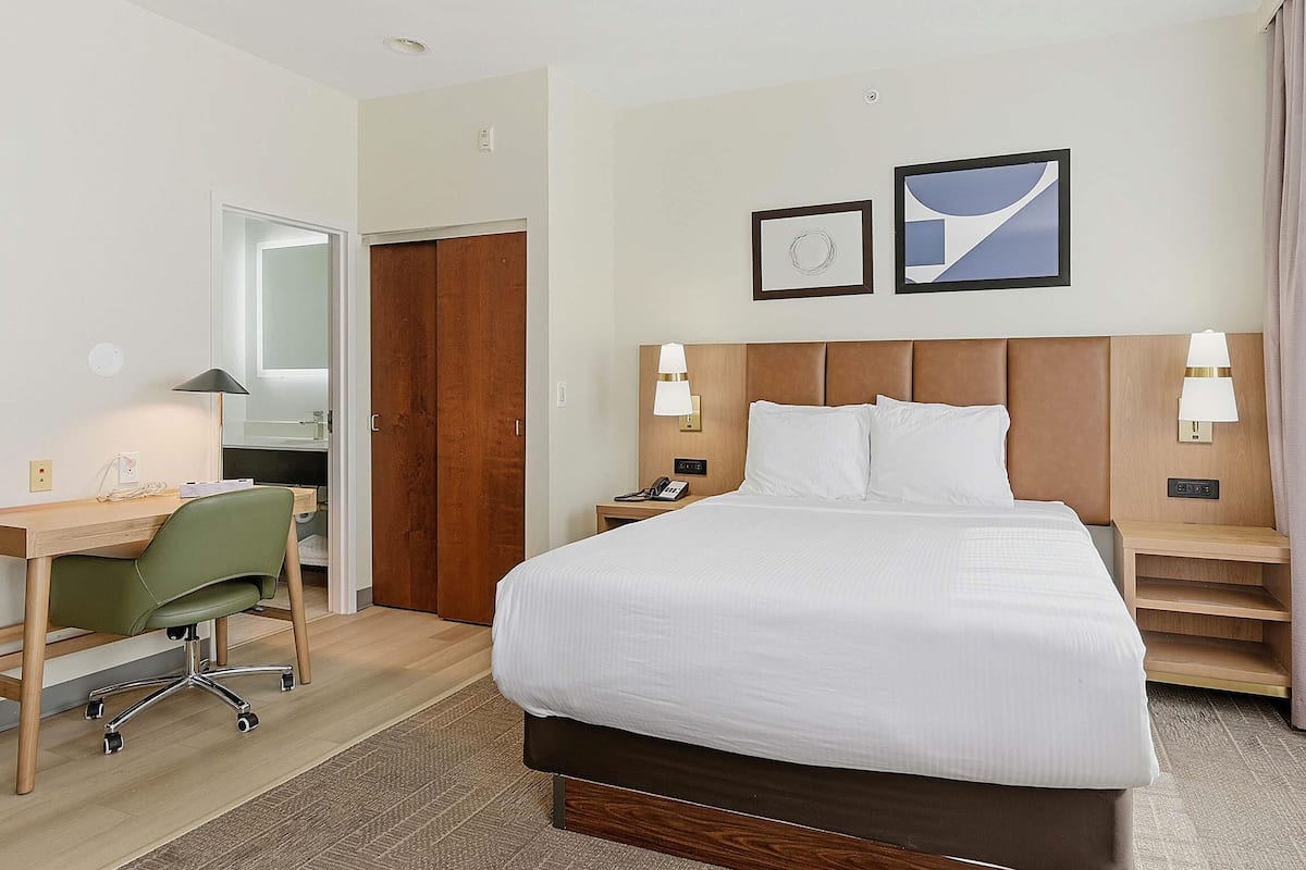 Una habitación de hotel con cama, escritorio, silla y armario.