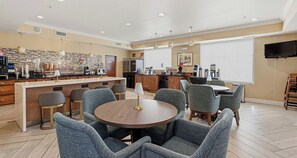 A modern kitchen with a bar area, seating for six, and a flat-screen TV. - Best Western Plus Hannaford Inn & Suites (Cincinnati)