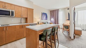 A modern kitchen with wooden cabinets, a microwave, and a bar area with stools.