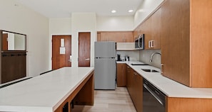 A modern kitchen with wooden cabinets, a stainless steel refrigerator, a microwave, and a dishwasher. - Best Western Plus Hannaford Inn & Suites (Cincinnati)