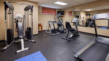 A gym with various exercise equipment, including a treadmill, elliptical, and weight machines.