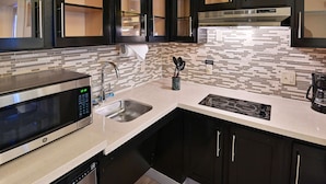 A modern kitchen with a built-in microwave, stainless steel sink, and a stove.