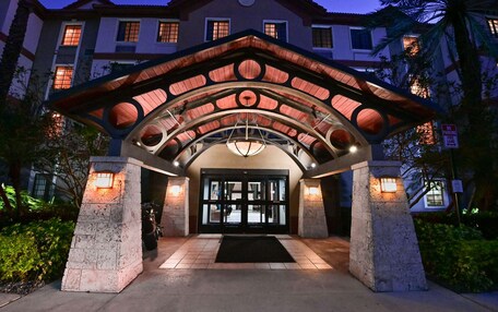 A hotel entrance with a covered entrance, a black door, and a stone pillar.
