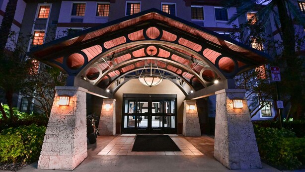 A hotel entrance with a covered entrance, a black door, and a stone pillar.