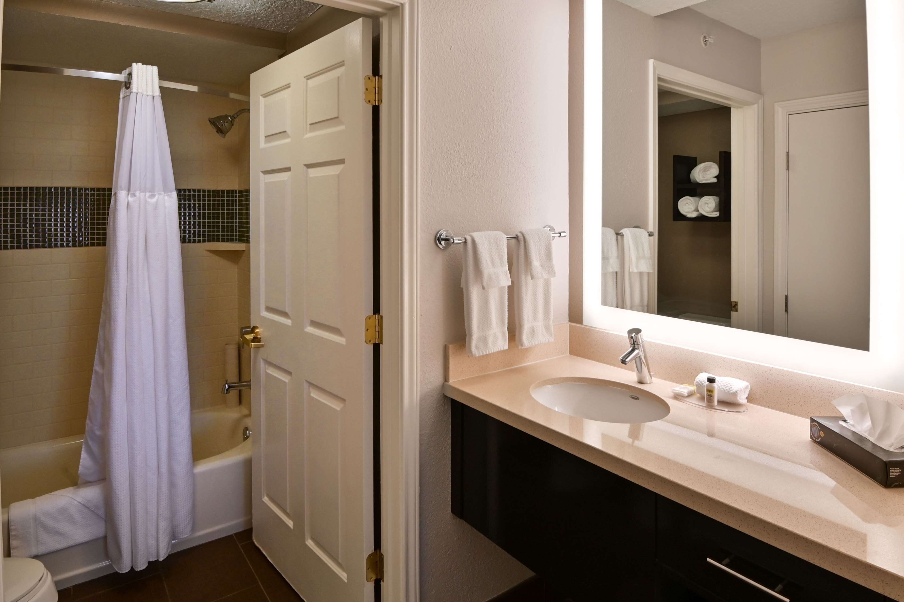 A bathroom with a bathtub, a sink, and a mirror.