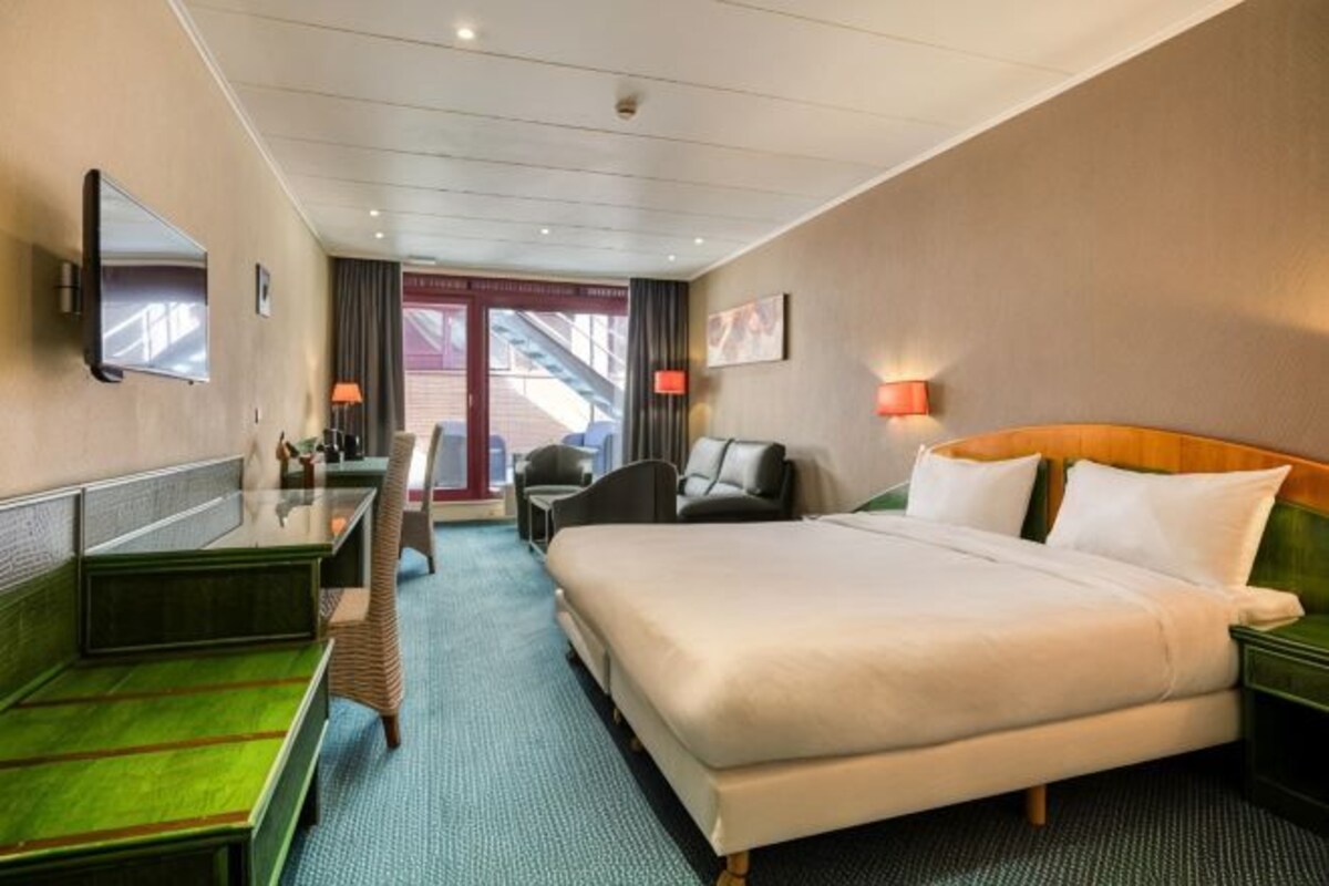 Een hotelkamer met een bed, bureau, stoel en een televisie.
