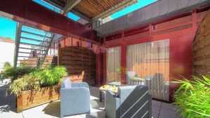 An outdoor patio with wicker furniture, a wooden planter with plants, and a brick wall. - B&B HOTEL Mons Centre (Mons)