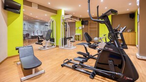 A gym with cardio machines, a weight bench, and a mirror. - B&B HOTEL Mons Centre (Mons)