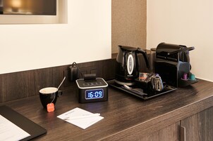 Una recepción de hotel con un reloj digital, una cafetera, una taza y una tableta.