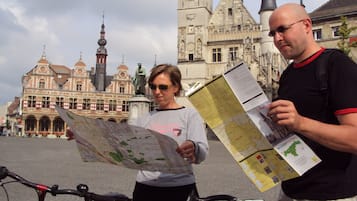 Due persone che tengono in mano mappe di fronte a un edificio storico con una torre dell'orologio.