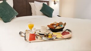 A neatly made breakfast tray with croissants, pastries, cheese, and cured meats on a hotel bed. - Keizershof Hotel (Aalst)
