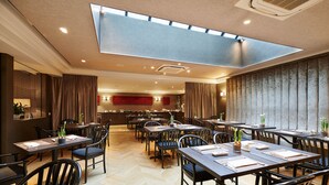 A modern restaurant with high ceilings, a skylight, and a herringbone floor pattern. - Keizershof Hotel (Aalst)