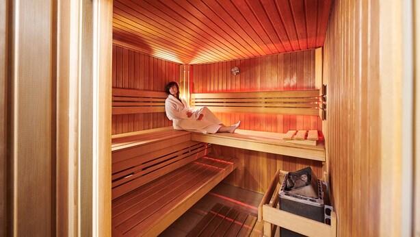 A sauna with wooden benches and a bench with a towel. - Keizershof Hotel (Aalst)