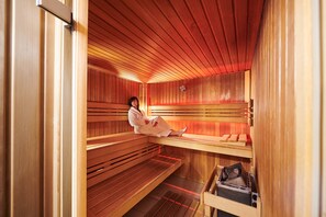 A sauna with wooden benches and a bench with a towel. - Keizershof Hotel (Aalst)
