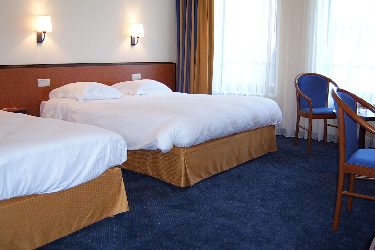 A hotel room with two beds, a desk, and a chair.