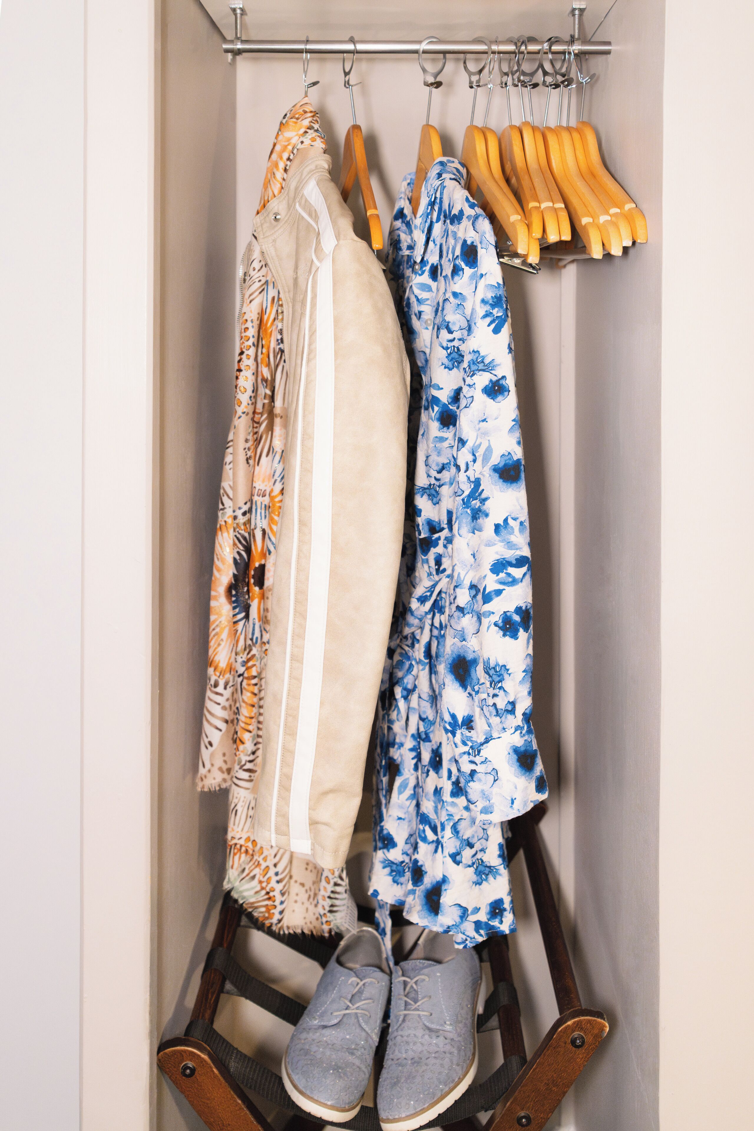 A closet with hanging clothes and shoes.