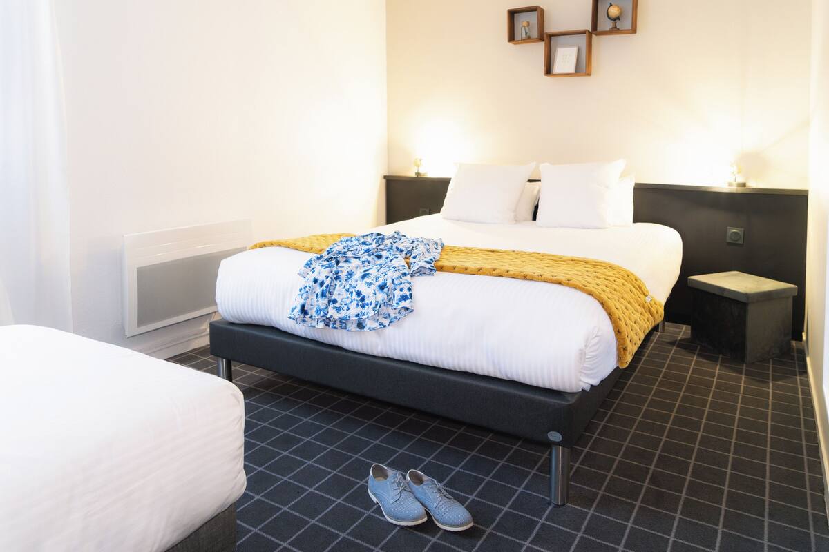 Ein Hotelzimmer mit einem Bett, Nachttischen und einem Paar Schuhen auf dem Boden.