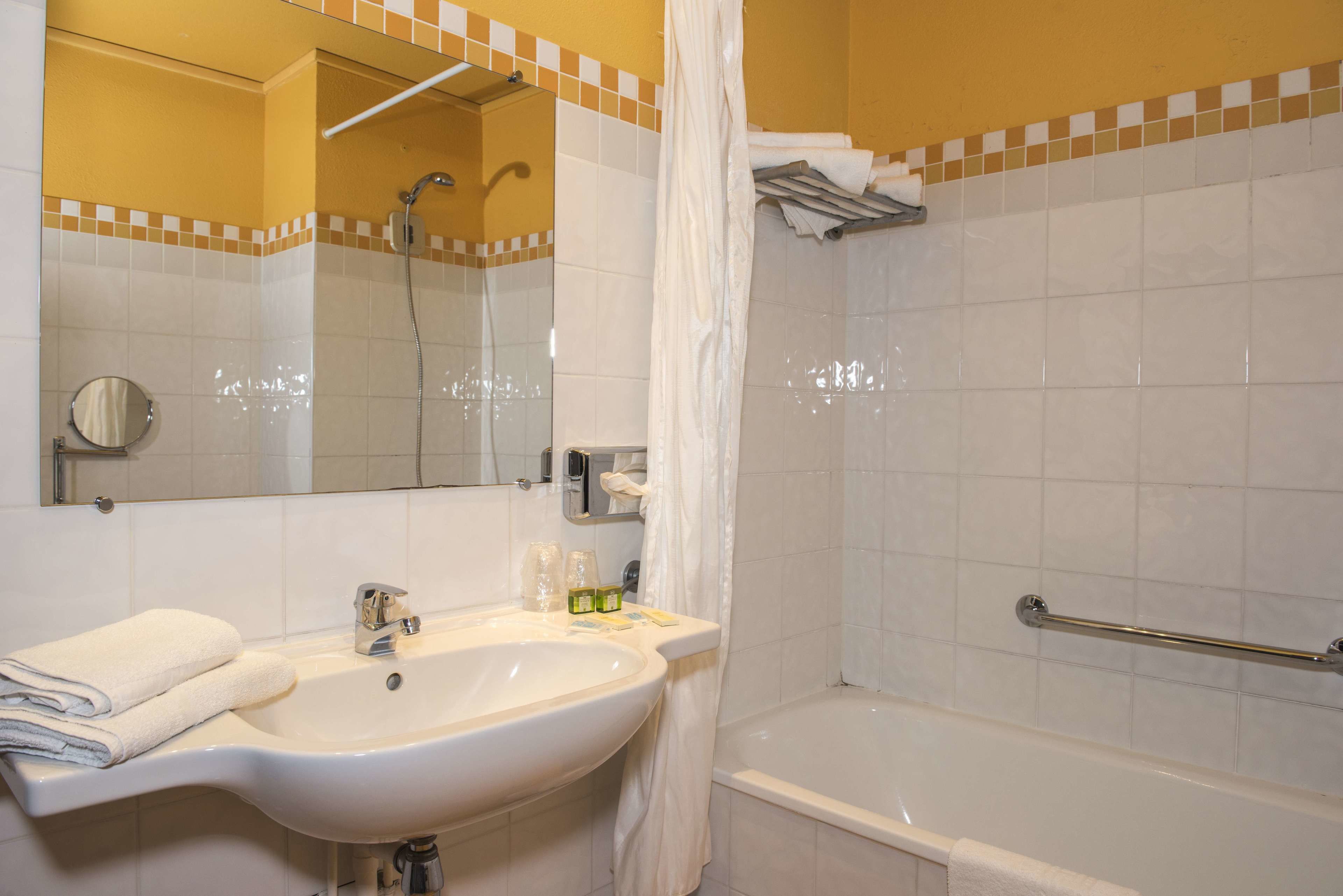 Une salle de bain équipée d’un lavabo, d’un miroir, d’une douche et d’une baignoire.