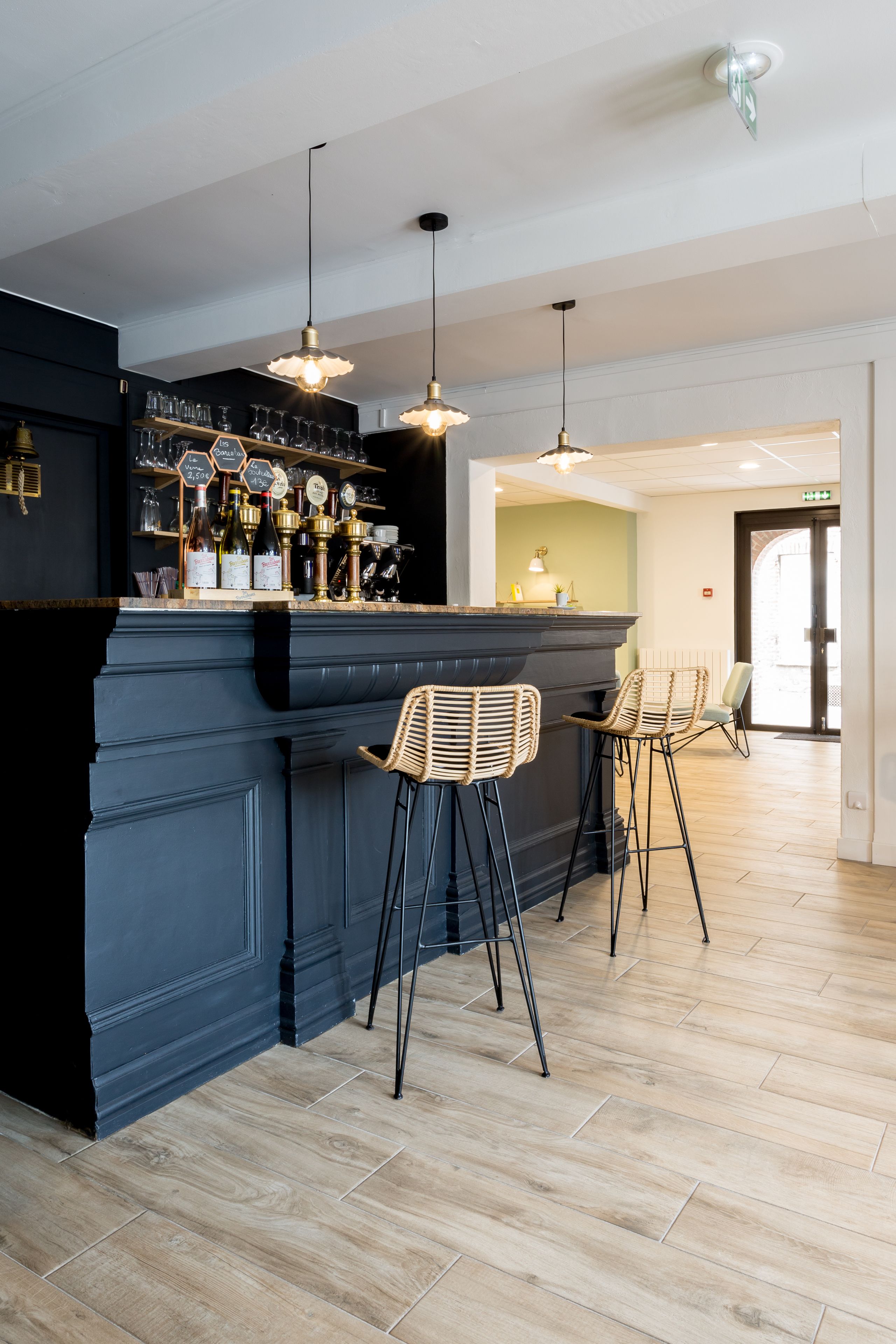 Un espace bar avec un comptoir sombre, des tabourets de bar et des luminaires suspendus.