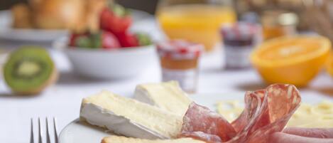 Un plato de desayuno con queso, jamón y huevos.