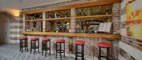 A bar area with brick walls, wooden shelves, and red bar stools.