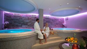 Dos jacuzzis con paredes de piedra y un frutero en los escalones.