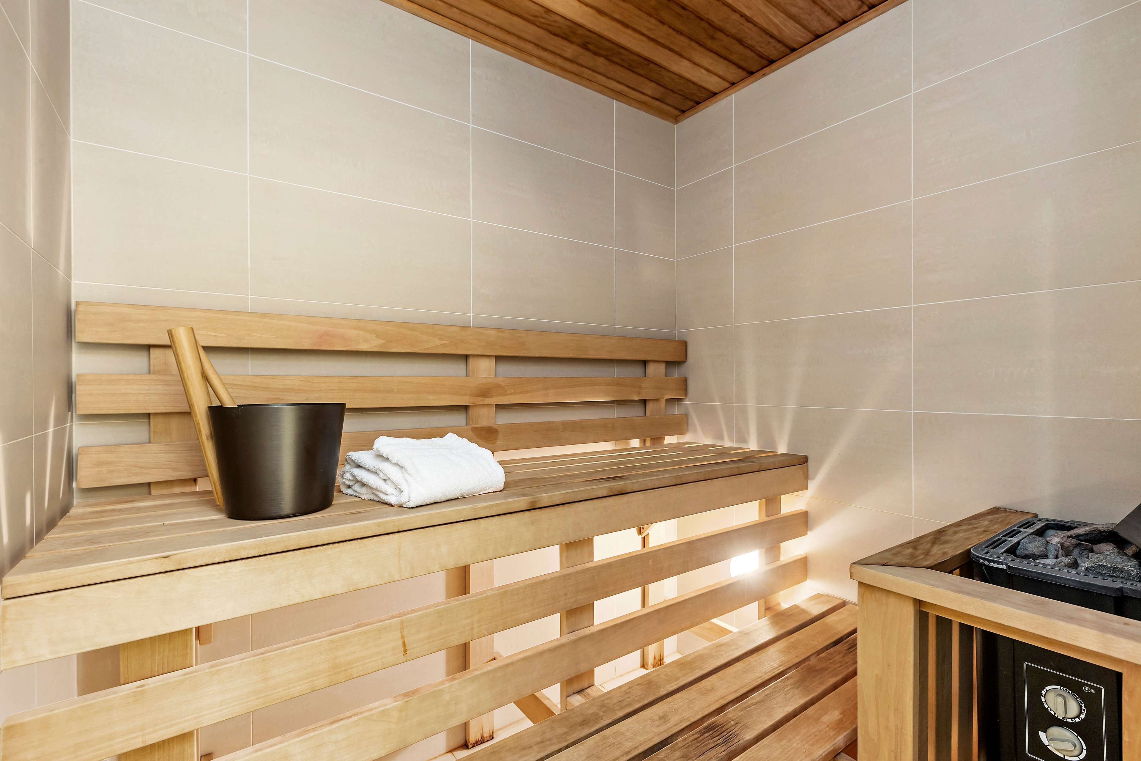 A sauna with wooden benches, a black bucket, and a towel.