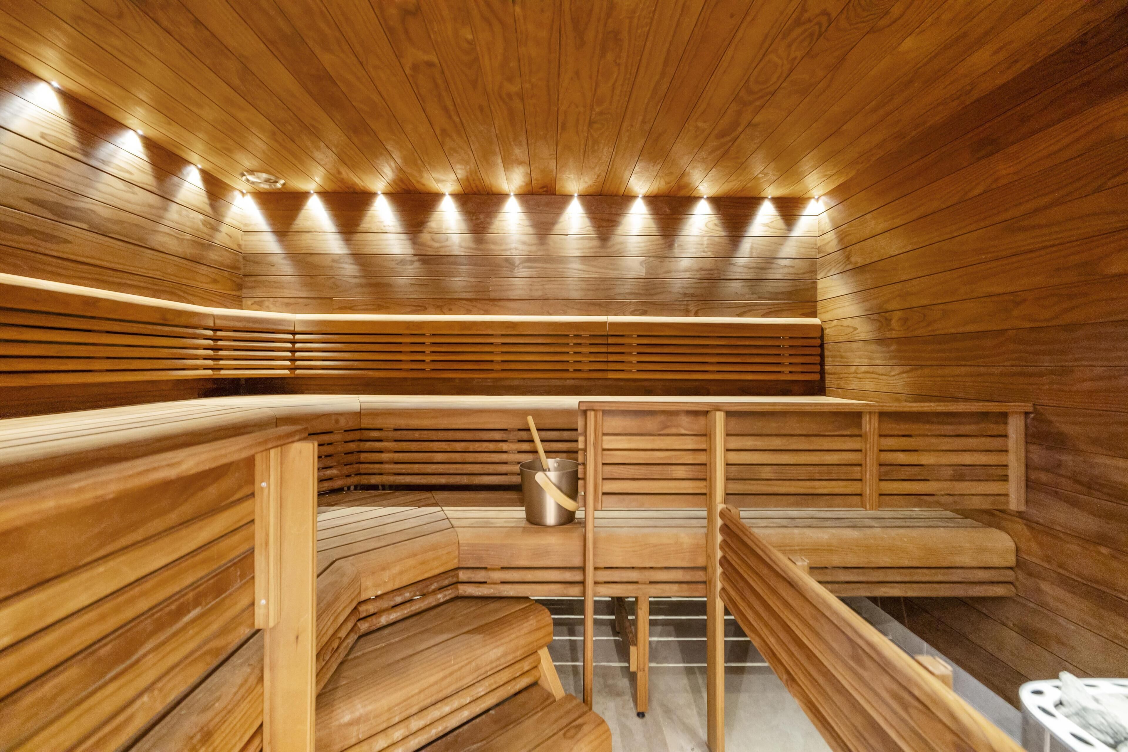 Una sauna con bancos de madera y un cubo de metal.