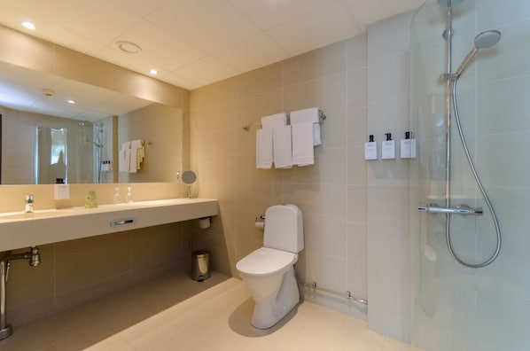 Un baño moderno con cabina de ducha de vidrio, inodoro y tocador con espejo.