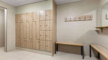 A restroom with wooden lockers, a bench, and a wall-mounted towel rack.