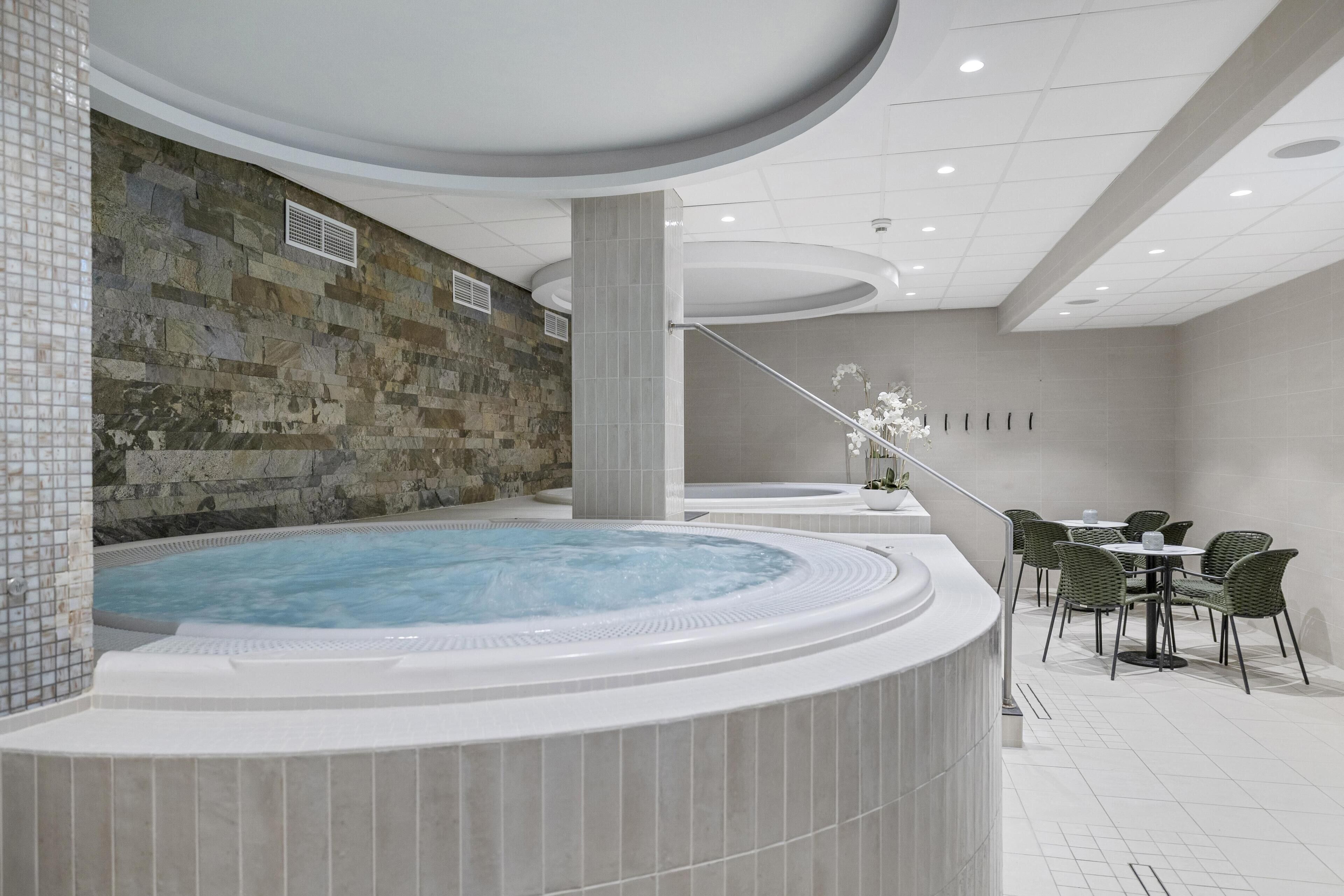 Un área de spa con jacuzzi, pared de piedra y zona de estar.