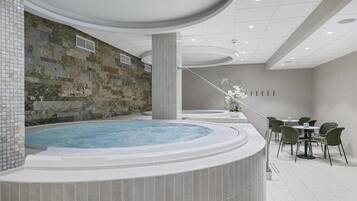 Un área de spa con jacuzzi, pared de piedra y zona de estar.
