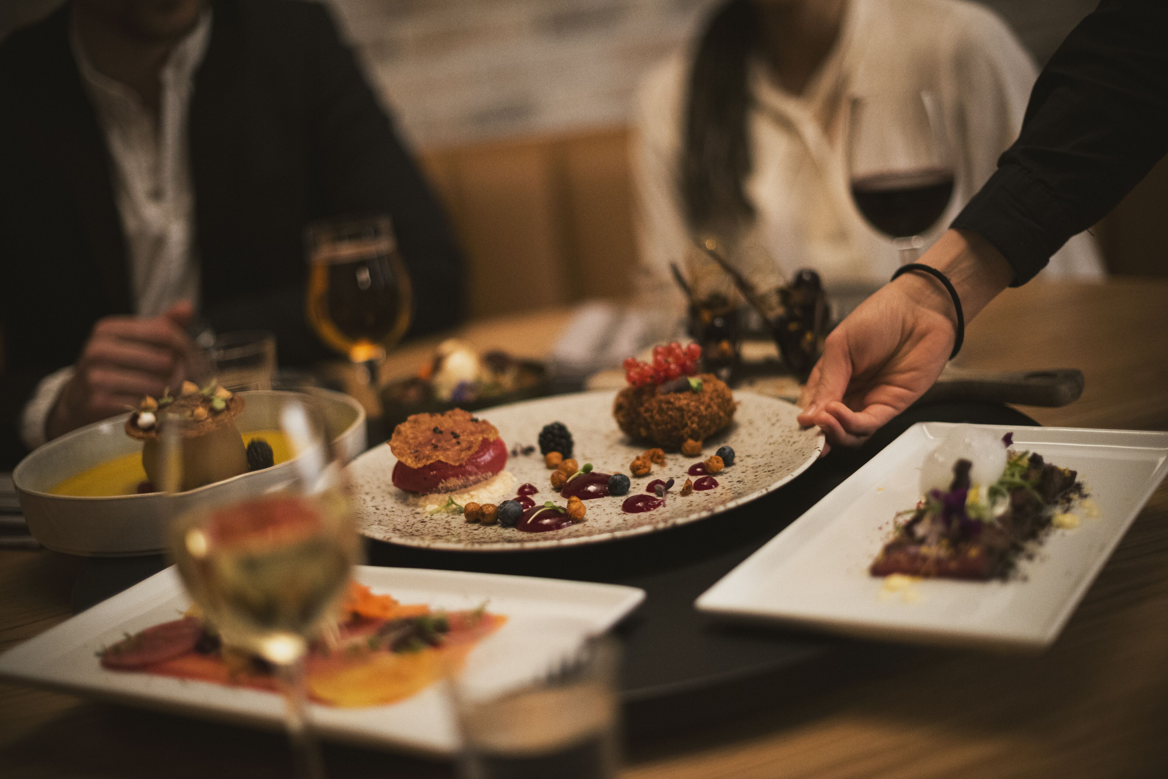 A dining table with various dishes and glasses of wine.