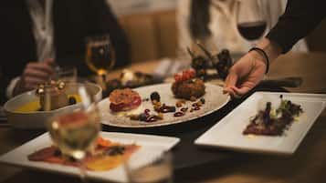 A dining table with various dishes and glasses of wine.