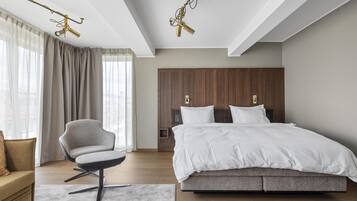 Un dormitorio moderno con una cama grande, una silla, un armario de madera y una lámpara en el techo.