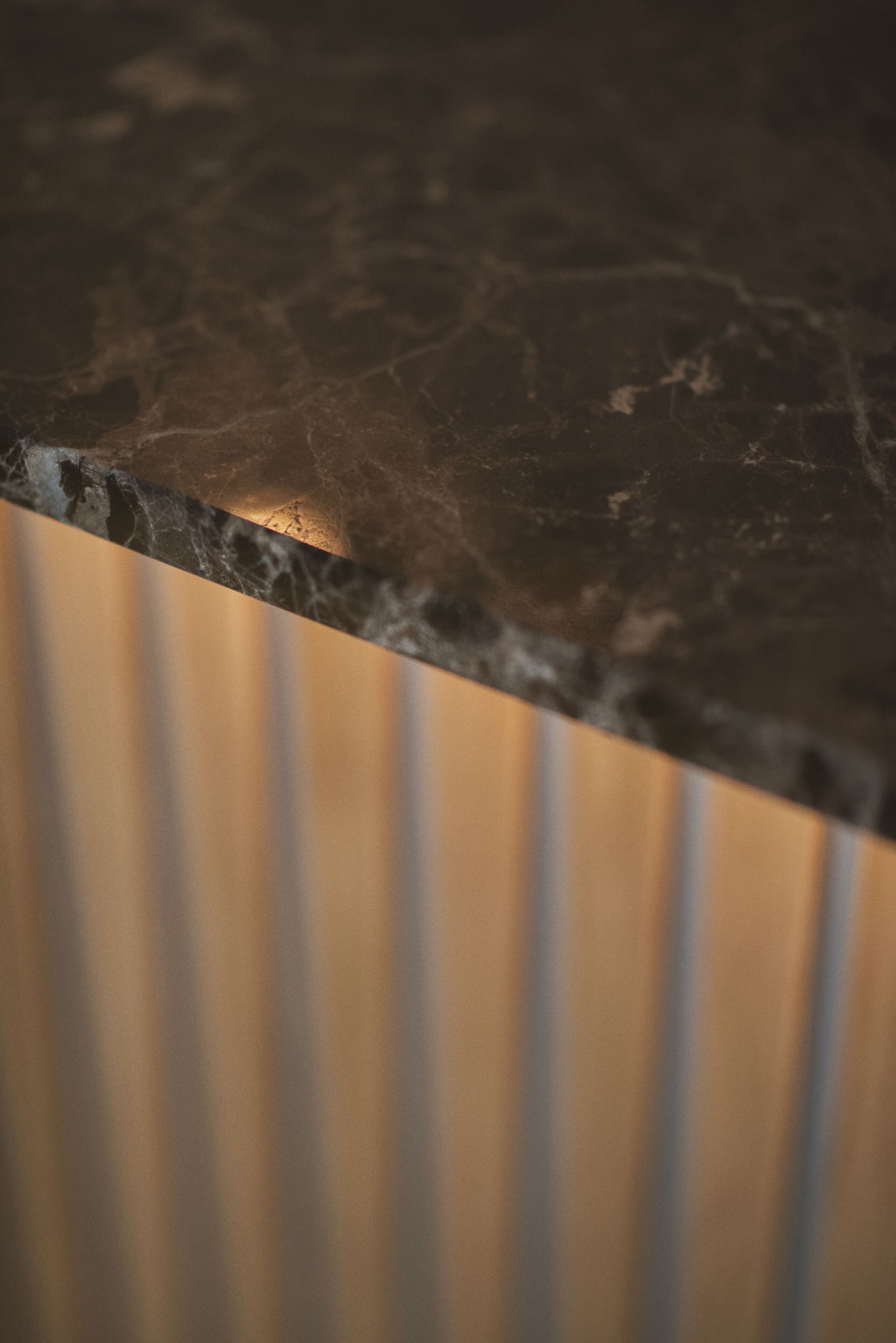 A close-up of a marble countertop with a wooden panel beneath.