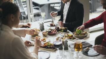 Un grupo de personas comiendo en una mesa con varios platos, copas de vino y un ambiente relajado.