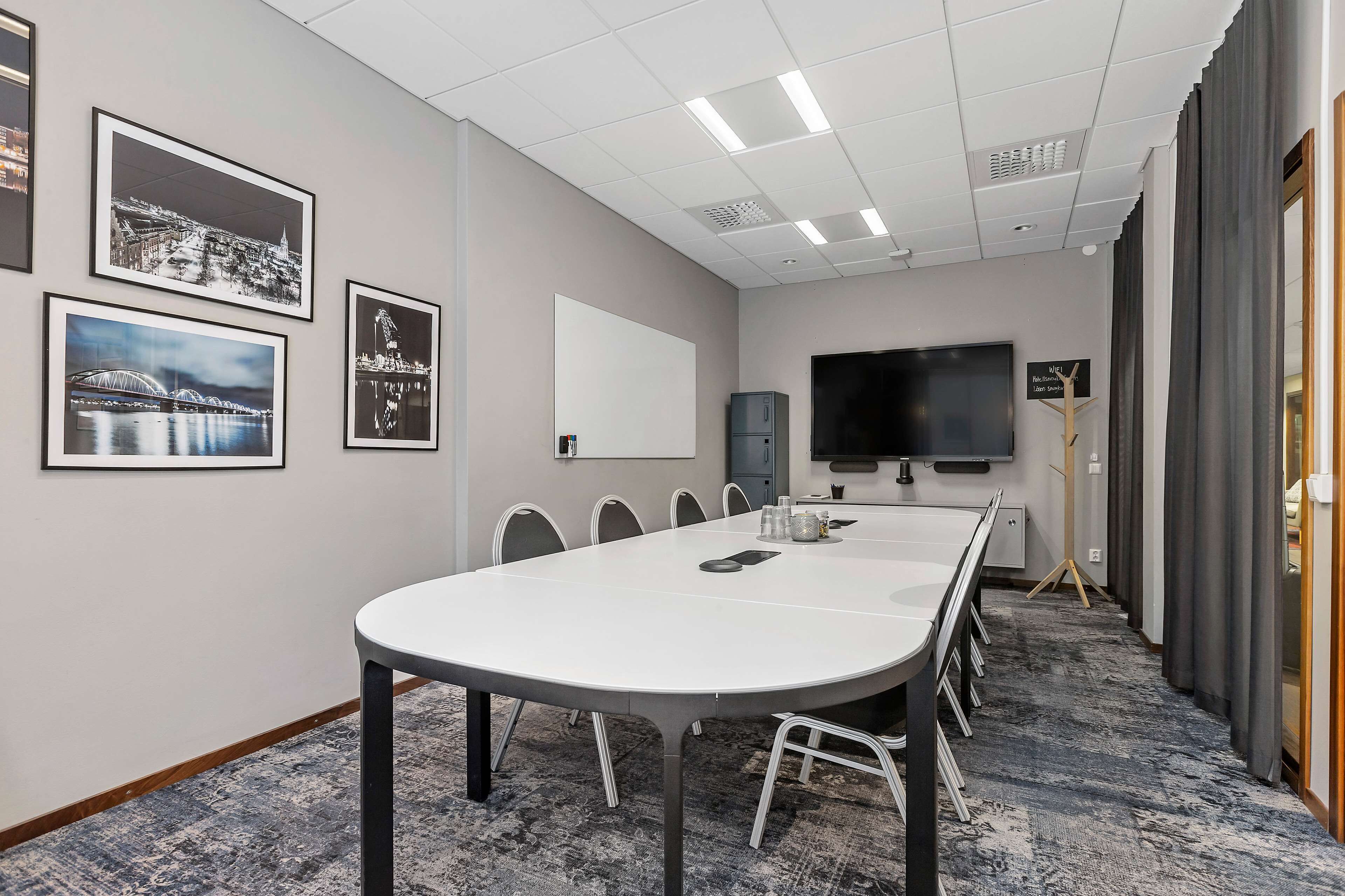 A conference room with a long table, chairs, a whiteboard, and framed pictures on the wall.