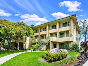 A multi-story building with a green roof, a central staircase, and a well-maintained garden with rocks and shrubs.