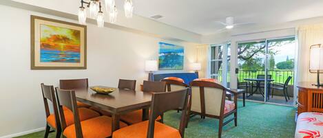 A dining area with a table and chairs, a chandelier, and a painting on the wall.