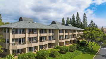 A multi-story hotel with balconies, a flat roof, and a landscaped garden.