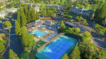 Un complexe hôtelier comprenant plusieurs bâtiments, une piscine, des courts de tennis et des panneaux solaires.