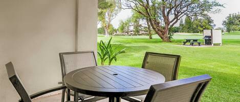 Une terrasse extérieure avec une table ronde et des chaises, donnant sur un terrain de golf.