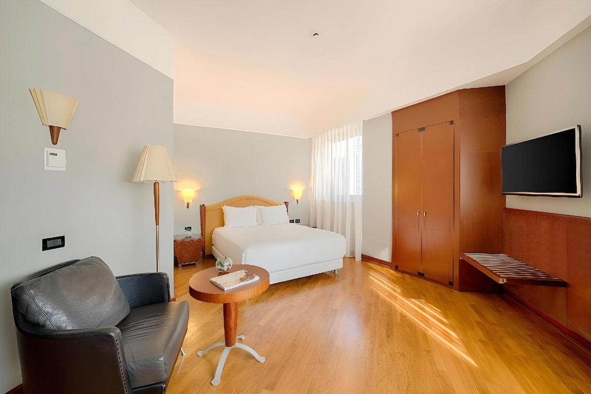 Une chambre d’hôtel comprenant un lit, un bureau, une chaise, une télévision et une armoire.