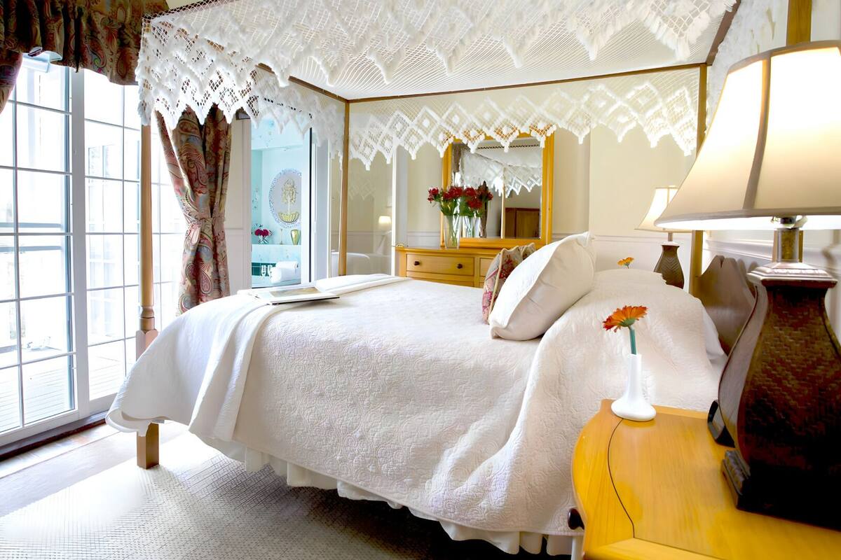 A hotel room with a large bed, a dresser, a mirror, and a window with curtains.